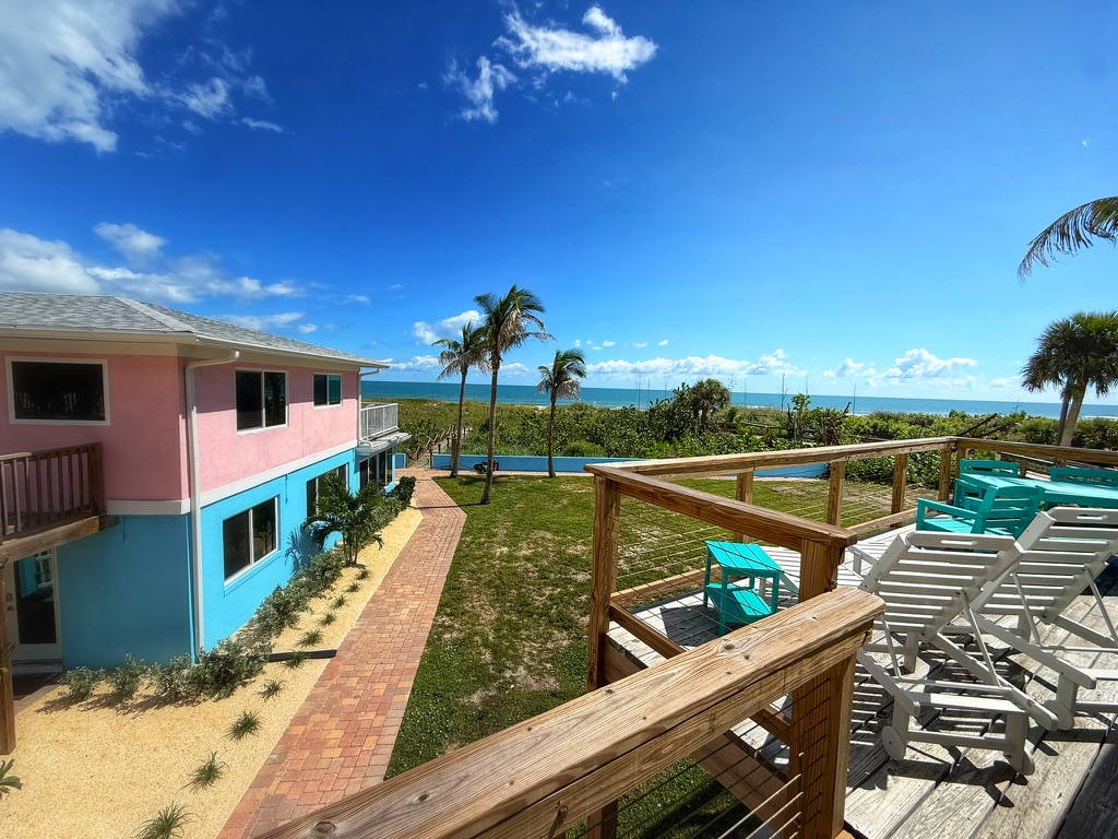 Canaveral Beachfront Villas with pink and turquoise buildings, palm trees, ocean views, and deck seating