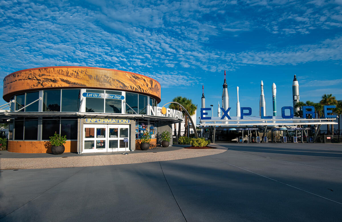 Kennedy Space Center Visitor Complex front entrance with the blue EXPLORE sign and Rocket Garden