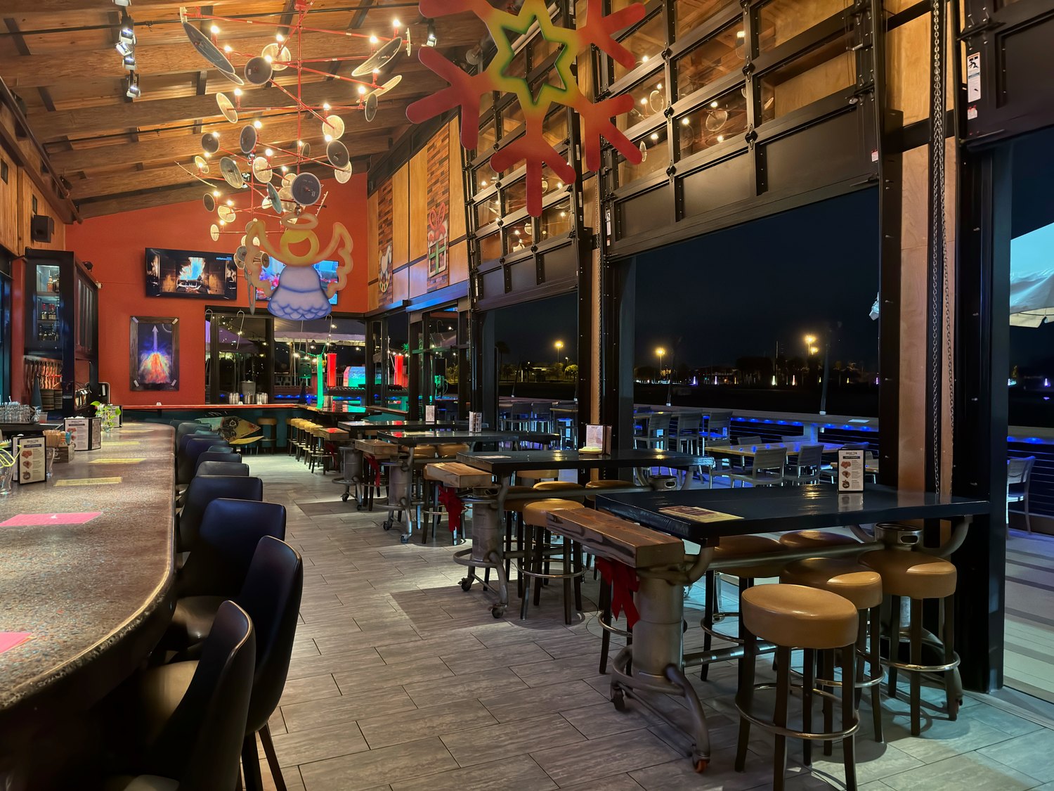 Rising Tide at the Port interior at night, with bar seating and an open-air dining area